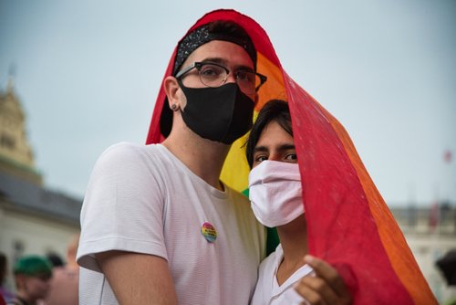 Warsaw, Poland, June 2020: LGBT supporters wearing face masks protesting on the street with rainbow flags. Concept of gay couples rights