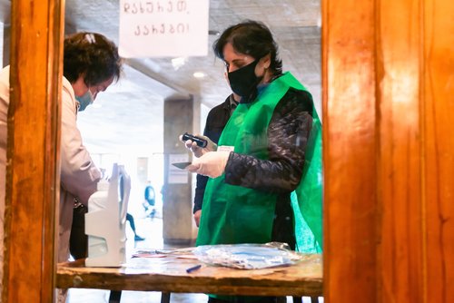 Tbilisi, Republic of Georgia- 31 October,2020.Georgian parliament elections. Woman at security checks female citizen ID and holds stamp before letting to ente to vote.