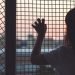 Woman's-hand-grabs-the-fence-Greece