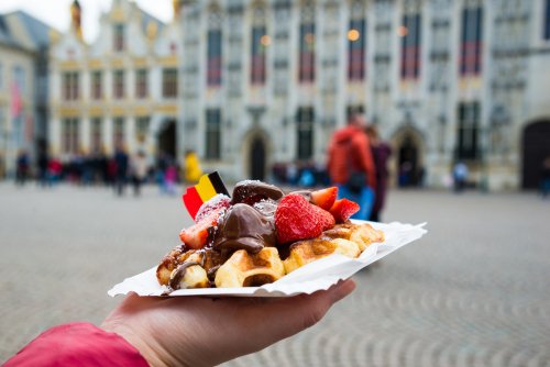 Belgium,Waffle,With,Chocolate,Sauce,And,Strawberries,,Bruges,City,Background,