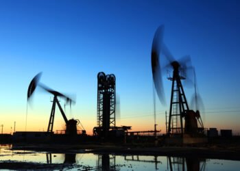 Oil field site, in the evening, oil pumps are running, Silhouette of beam pumping unit