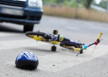 A small bike and a helmet lying on the road