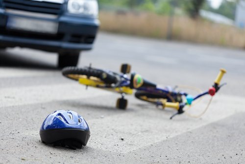 A small bike and a helmet lying on the road