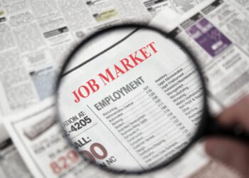 Magnifying glass over a newspaper classified section with Job Market text