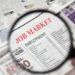 Magnifying glass over a newspaper classified section with Job Market text