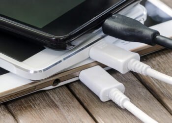 Stack,Of,Smart,Phone,Charging,With,Cable,On,The,Wooden