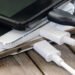 Stack,Of,Smart,Phone,Charging,With,Cable,On,The,Wooden