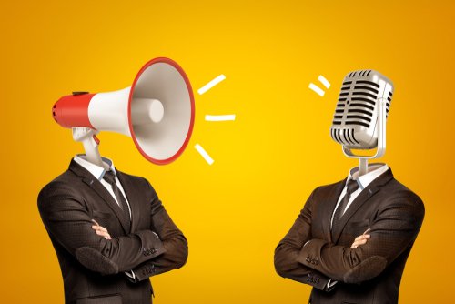 Waist-deep view of two businessmen standing in half-turn, arms folded, with megaphone and microphone instead of heads. Opinion leaders. Media influence public opinion. Media and people.