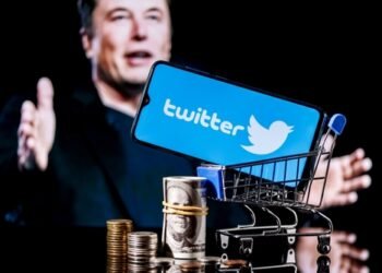 Kazan, Russia - Apr 26, 2022: Logo of social network Twitter on smartphone screen in shopping cart with money and photo Elon Musk in background. Elon Musk reaches agreement to acquire Twitter.