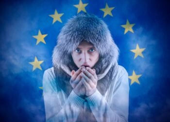Increase in the price of natural gas for home heating. Transition to renewable energy sources. Energy crisis in Europe. A citizen of Europe freezes in front of the flag.