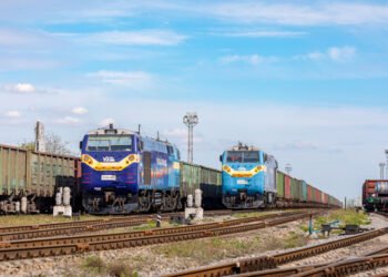 Mariupol, Ukraine - Spring 2021: Two new TE33 locomotives with long freight trains stand at a transit railway station. Train with steel products. Ukrainian railway