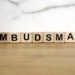 Ombudsman word from wooden blocks on desk, public administration concept