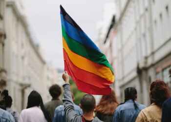 Rear view of people in the pride parade. Group of people on the city street with gay rainbow flag.