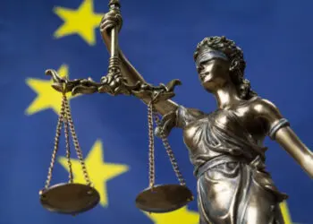 Statue of the blindfolded goddess of justice Themis or Justitia, against an European flag, as a legal concept