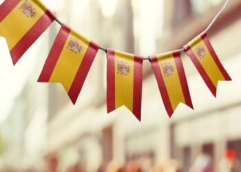 A garland of Spain national flags on an abstract blurred background.