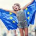 Cute happy young girl with the flag of the European Union.