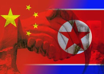 Giant stone handshake shining through the chinese and north korean flag partnership concept