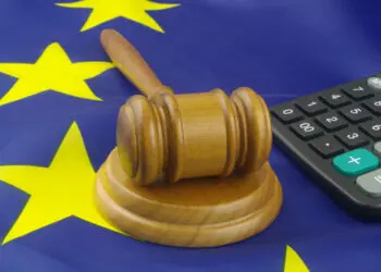 Wooden judge gavel and calculator on European Union flag. Arbitration court and financial fraud in EU concept.
