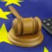 Wooden judge gavel and calculator on European Union flag. Arbitration court and financial fraud in EU concept.