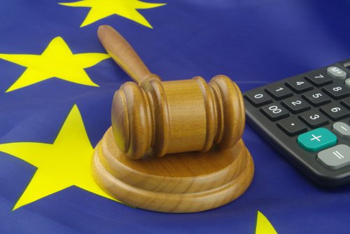 Wooden judge gavel and calculator on European Union flag. Arbitration court and financial fraud in EU concept.