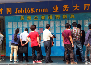 GUANGZHOU, CHINA, MARCH 20, 2012: People looking for jobs browse vacations on street board. Street advertisements and job boards are popular places for unemployed.