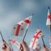 A group of people holding small flags of the Georgia in their hands.